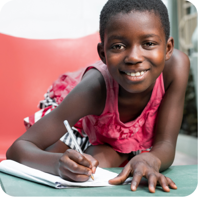 Picture with Girl writing on a book while smiling and looking at the camera